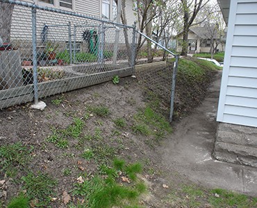Side yard of gray home before retaining wall installation